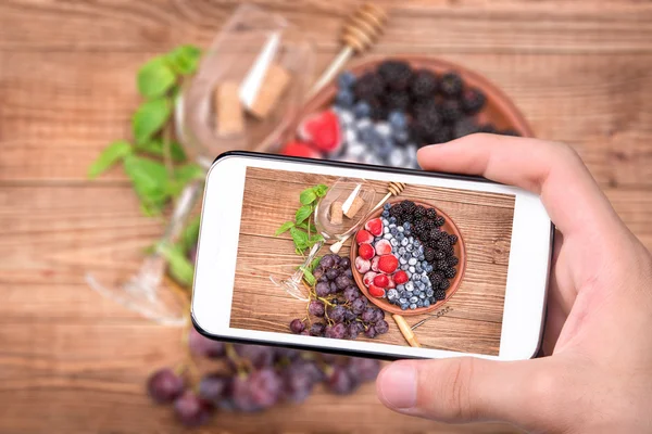 Ręce biorąc zdjęcie czerwone wina sangria z świeże jagody z smartphone. — Zdjęcie stockowe