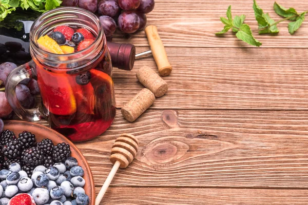 Sangria casera de vino tinto con bayas frescas sobre una mesa de madera . —  Fotos de Stock