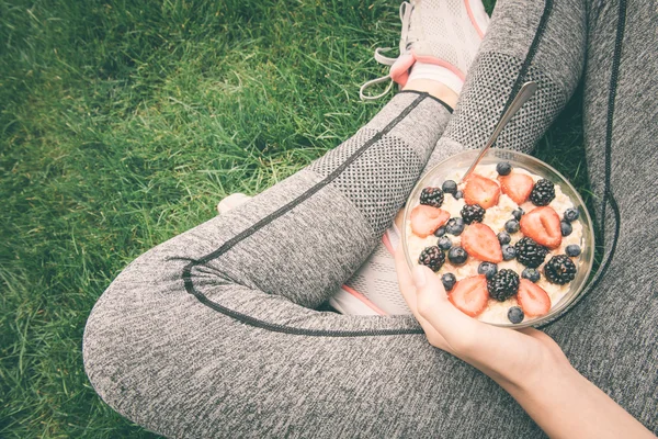 Young girl eating a oatmeal with berries after a workout . Fitness and healthy lifestyle concept.