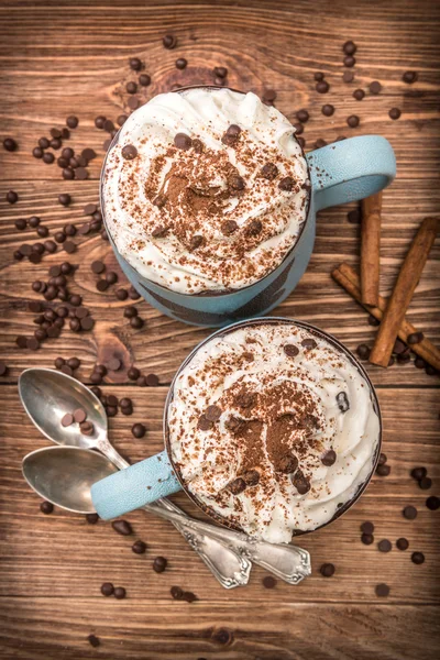 Cokelat panas dengan krim kocok di cangkir di atas meja kayu . — Stok Foto