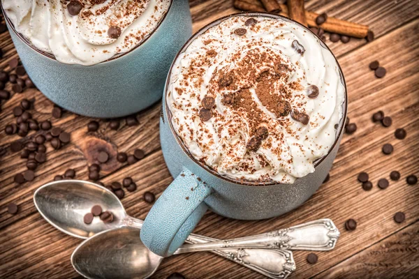 Chocolat chaud avec crème fouettée dans une tasse sur une table en bois . — Photo