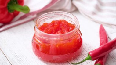 Küçük kaşıkla acı biber jölesi tatmış bir kadın. Tatlı dolma biber ve biber sosu, ziyafet, kavanozda reçel..