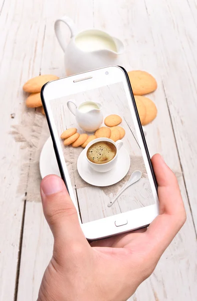 Руки делают фото кофе со смартфоном — стоковое фото