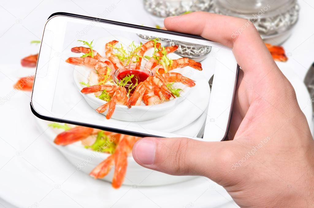 Hands taking photo shrimps with smartphone.