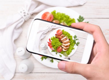 Eller fotoğraf tavuk göğsü ile smartphone alarak.
