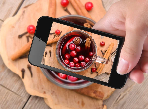 Manos tomando vino caliente con foto con teléfono inteligente . — Foto de Stock