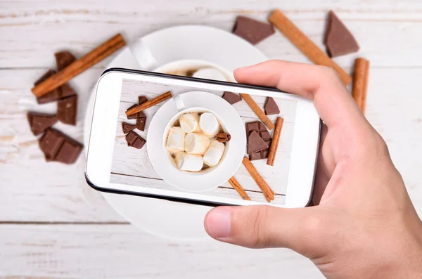 Hände, die heißen Kakao mit dem Smartphone fotografieren. — Stockfoto