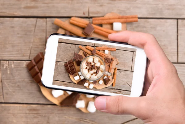 Handen nemen foto warme chocolademelk met smartphone. — Stockfoto