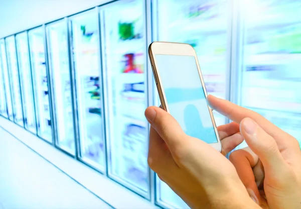 Het winkelen lijst op haar smartphone in supermarkt. — Stockfoto