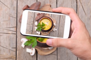 Foto mantar çorbası ile smartphone alarak eller.