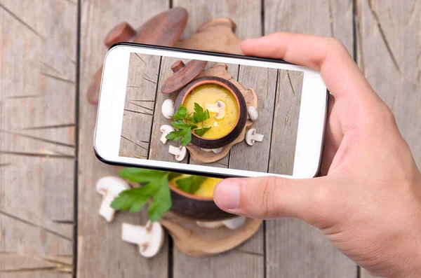 Hands taking photo mushroom soup with smartphone. — Stock Photo, Image