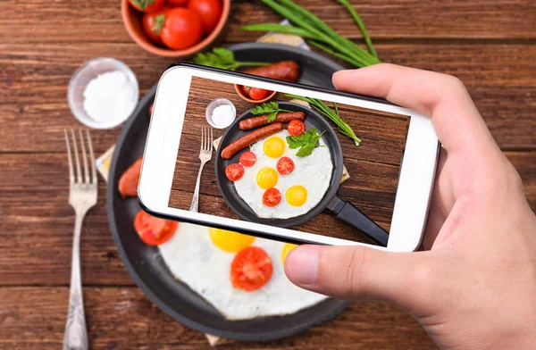 Hands taking photo eggs and sausage with smartphone — Stock Photo, Image