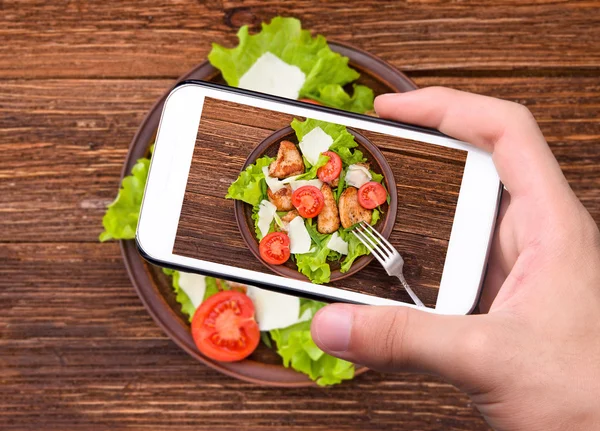 Manos tomando foto ensalada de verduras con carne con smartphone — Foto de Stock