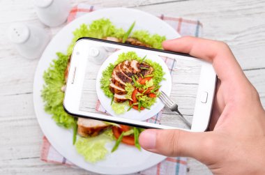 Eller fotoğraf tavuk göğsü ile smartphone alarak.