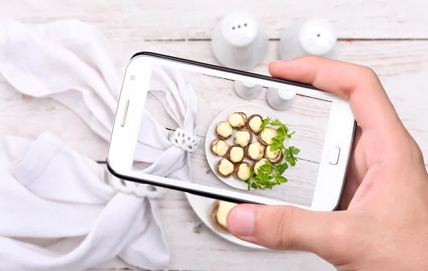 Hände fotografieren Pilze mit Käse mit dem Smartphone. — Stockfoto