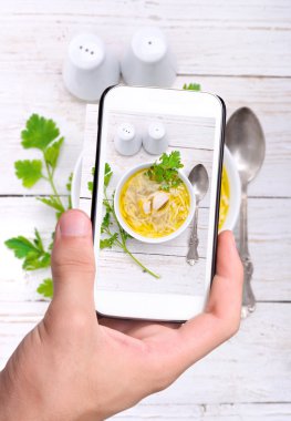 Eller fotoğraf tavuk çorbası ile smartphone alarak.