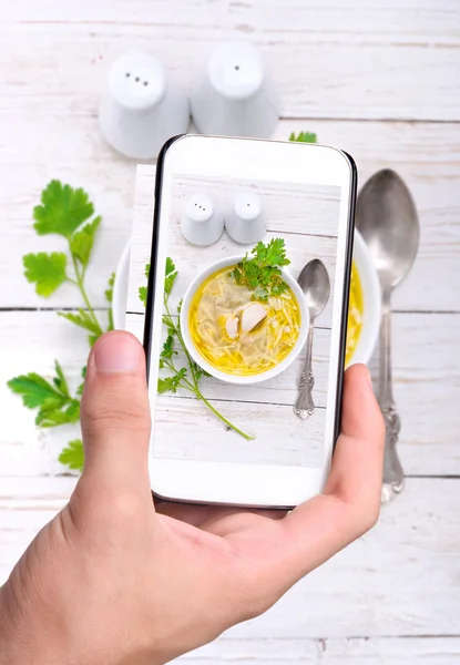 Mani che scattano foto zuppa di spaghetti di pollo con smartphone . — Foto Stock