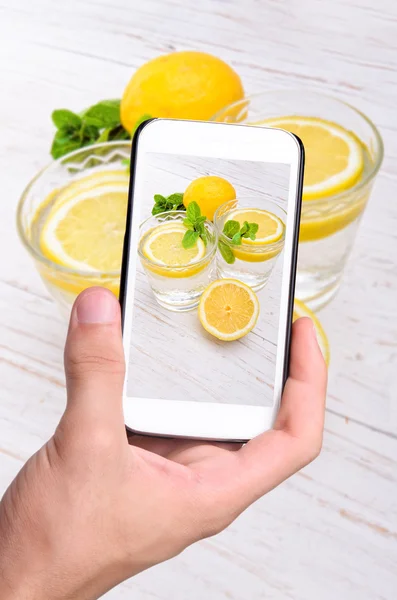 Händer med foto citron dricka med smartphone. — Stockfoto
