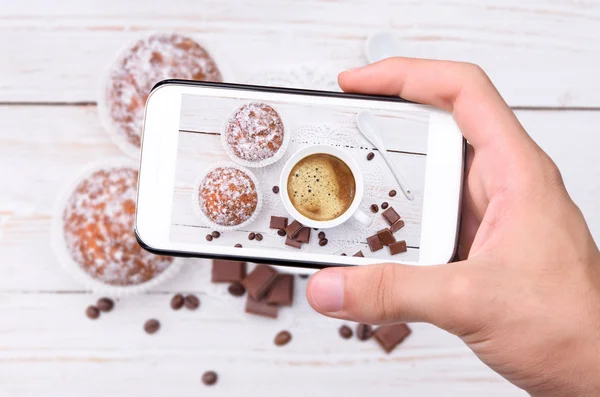 Mãos tirando foto xícara de café com bolo com smartphone . — Fotografia de Stock