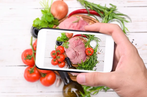 Manos tomando fotos de carne cruda con teléfono inteligente . — Foto de Stock