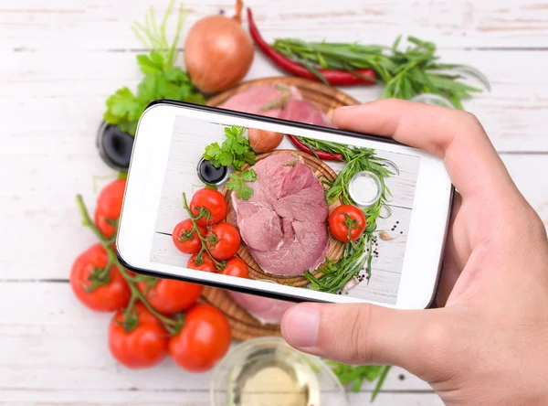 Mãos tirando foto carne crua com smartphone . — Fotografia de Stock