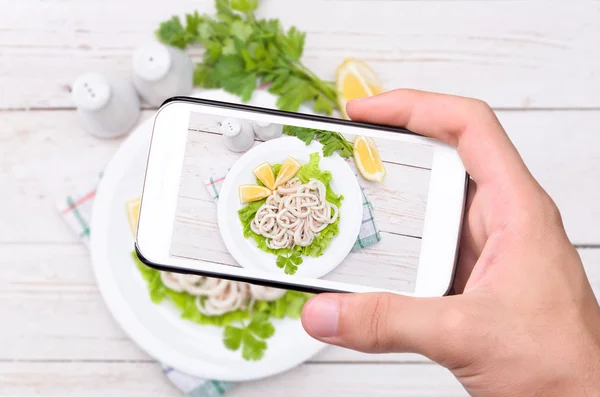 Mani che scattano foto calamari e limone con smartphone . — Foto Stock