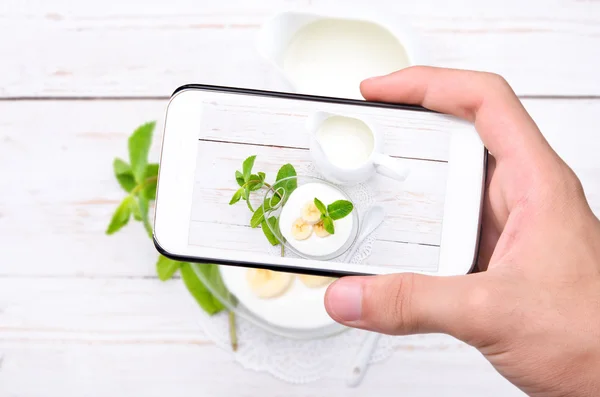 Mãos tirando iogurte foto com smartphone . — Fotografia de Stock