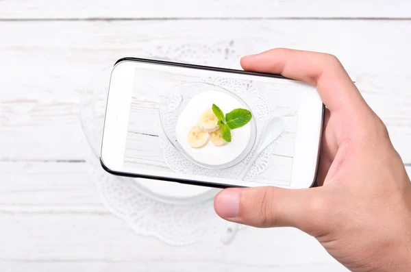 Händer med foto yoghurt med smartphone. — Stockfoto