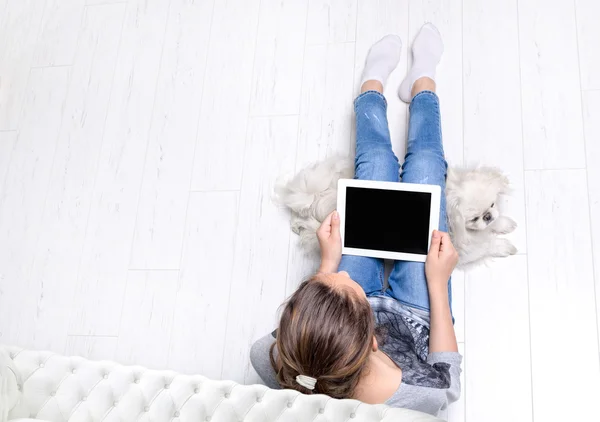 Молода жінка сидить на підлозі і використовує планшет  . — стокове фото