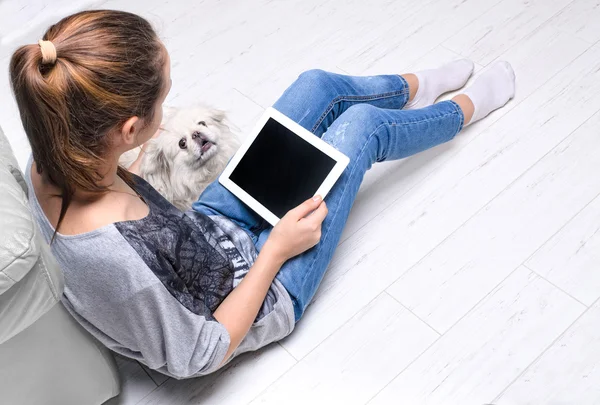 Молода жінка сидить на підлозі і використовує планшет  . — стокове фото