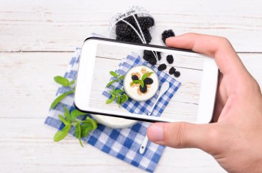 Eller fotoğraf Yoğurtlu müsli ve böğürtlen smartphone ile.