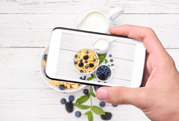 Manos tomando foto desayuno con copos de maíz con teléfono inteligente . —  Fotos de Stock