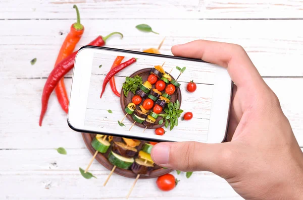 Mani che scattano foto verdure grigliate. con smartphone . — Foto Stock