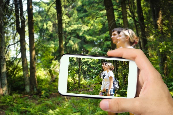 Руки фотографируют молодую девушку и мужчину в горах со смартфоном . — стоковое фото