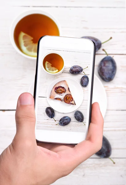 Hands taking photo plum cake with smartphone. — Stock Photo, Image