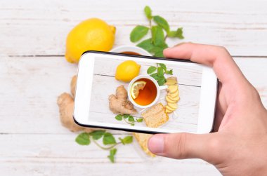 Smartphone ile fotoğraf zencefil çay içerken ellerin.