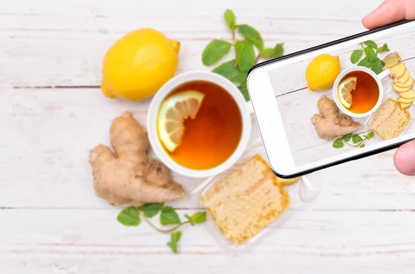Prendre des mains photo thé au gingembre avec smartphone . — Photo