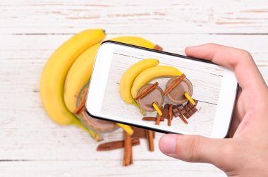 Eller fotoğraf çikolata muz smoothie smartphone ile alarak.