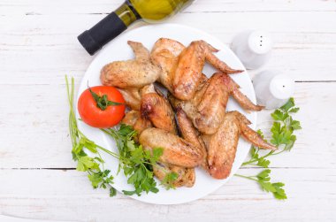 Beyaz bir tabak içinde pişmiş tavuk kanadı.
