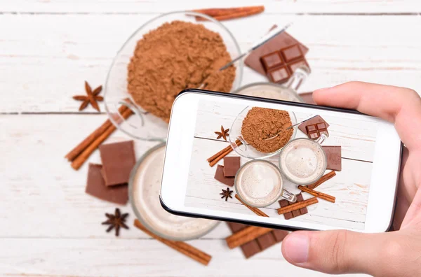 Handen nemen foto kopje heerlijke warme chocolademelk met smartphone. — Stockfoto