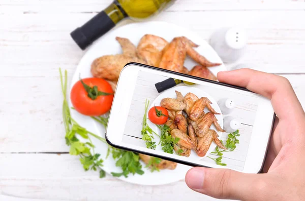 Manos tomando fotos de alas de pollo con smartphone . — Foto de Stock