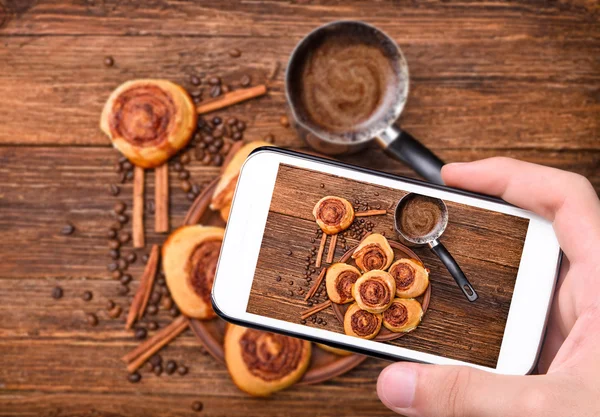 Hands taking photo cinnamon rolls with smartphone. — Stock Photo, Image