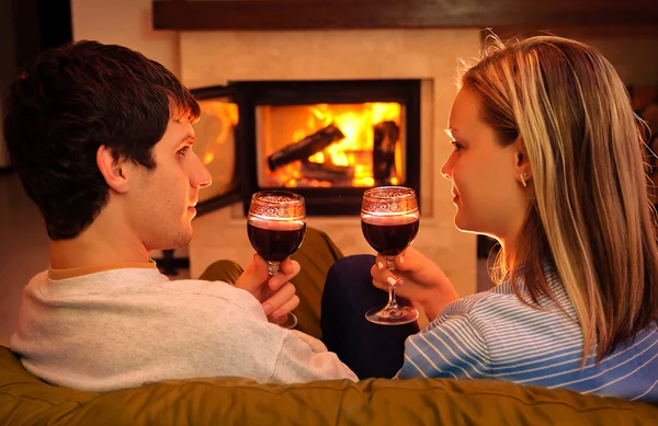 Mutlu genç çift oturma şömine yakın ve şarap içme — Stok fotoğraf