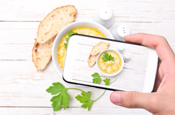 Händer med foto soppa med kyckling köttbullar med smartphone. — Stockfoto