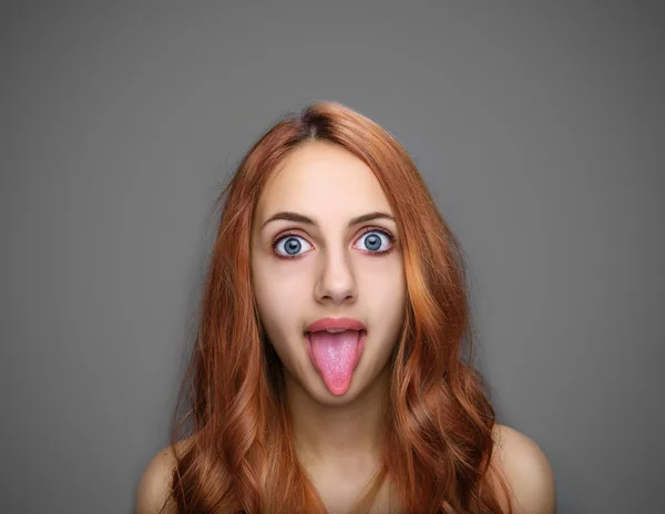 Girl showing tongue isolated on gray. — Stock Photo, Image