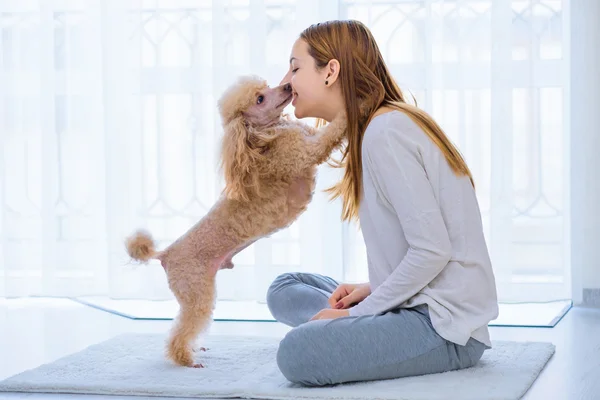 Ung flicka med sin hund på golvet hemma. — Stockfoto