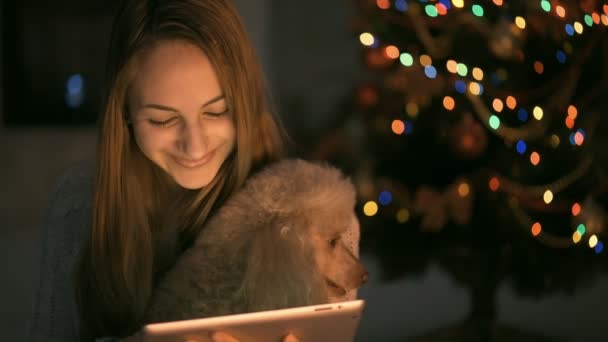 Young woman with her dog sitting on floor and using tablet . — Stock Video