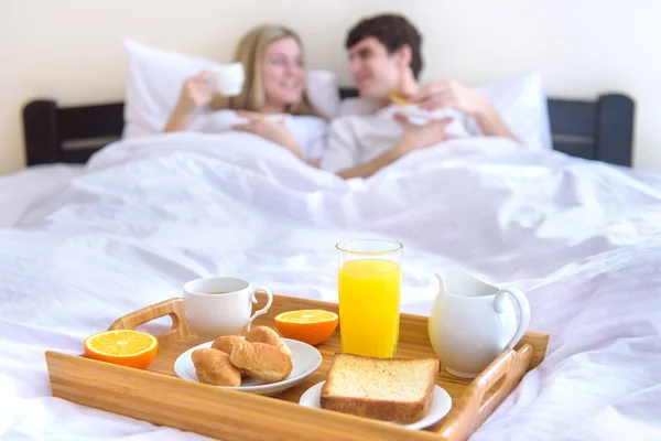 Glückliches junges Paar frühstückt im Bett . — Stockfoto
