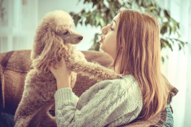 Genç kız evde koltuk üzerinde bir köpekle dinleniyor .