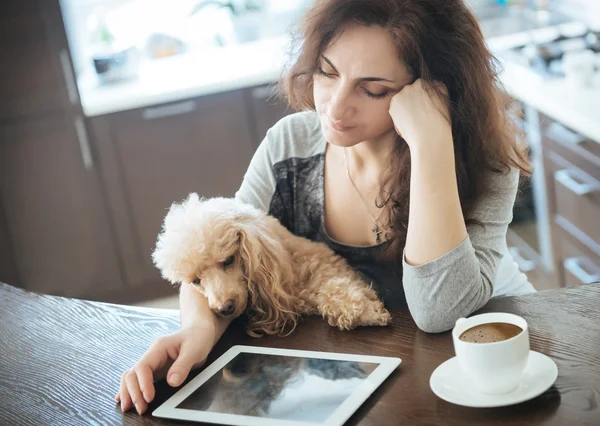 Jonge vrouwen rusten thuis met een hond en gebruiken een tablet . — Stockfoto